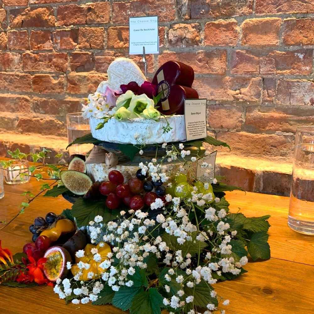 A tier of whole cheeses, styled for the day and delivered ready to place.